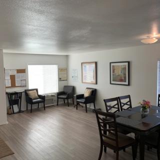 A spacious living and dining area featuring chairs, a table, and framed artwork on the walls.