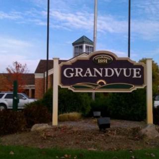 A sign for Grandvue in front of a building on a clear day.