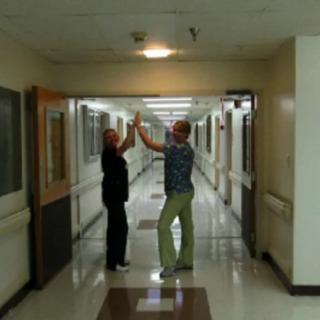 Two people sharing a high five in a hospital corridor.