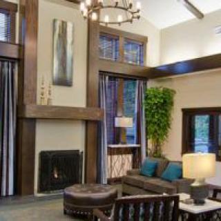 Modern living room with a fireplace and high ceilings, featuring elegant furniture and ample natural light.