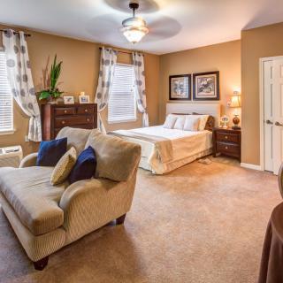 A cozy bedroom interior featuring a comfortable bed, a sofa, and elegant decor.