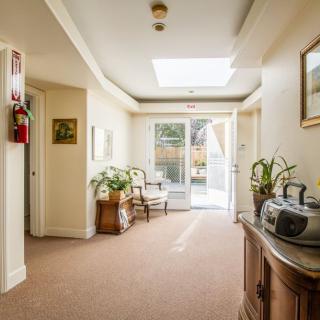 A bright hallway with traditional decor and natural light filtering through a skylight, featuring plants and wooden furniture.
