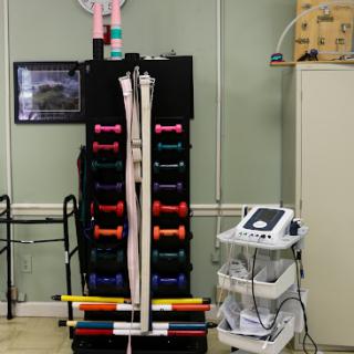A well-equipped rehabilitation room featuring a set of colorful dumbbells and medical equipment.