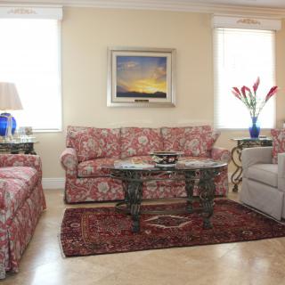 A cozy living room with patterned sofas, a glass-top table, and decorative elements.