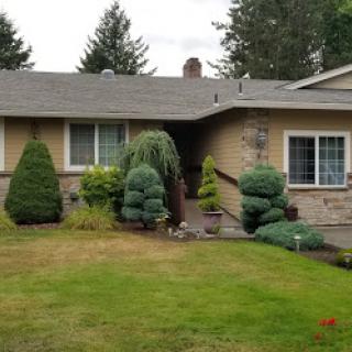 A charming single-story home with a well-maintained front yard and lush greenery.