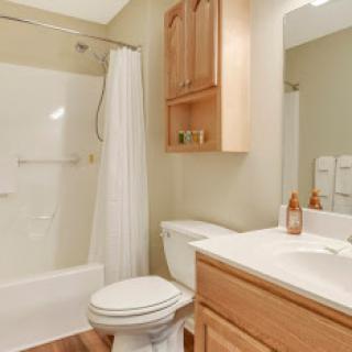 A well-lit bathroom featuring a shower, toilet, and vanity with storage.