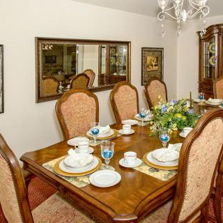A formal dining room with an elegantly set table, featuring china, glassware, and a floral centerpiece.