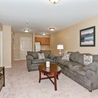 A cozy living room with a comfortable sofa and coffee table, leading into an open-plan kitchen.