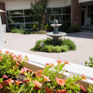 A courtyard garden with a central fountain surrounded by flowers and greenery.