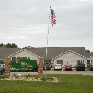 A building with an American flag and signage at the entrance, surrounded by parked cars.