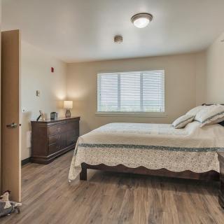 A cozy bedroom with a neatly made bed and wooden flooring.