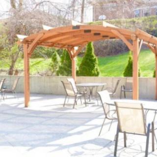A sunny outdoor patio with a wooden pergola and seating area.