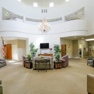 A spacious lobby with a central seating area, chandelier, and decorative plants.