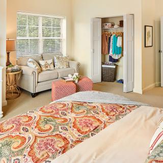 A cozy bedroom interior with a bed, sofa, and closet space.