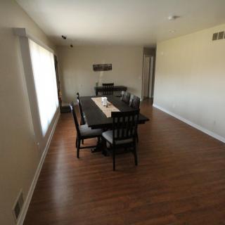 A minimalist dining room with a large table and chairs on a hardwood floor.