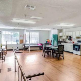A rehabilitation facility room with exercise equipment and a kitchen area.