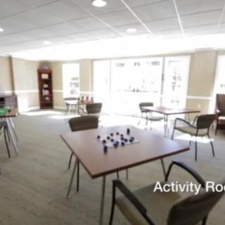 A bright activity room with tables and chairs arranged for various uses.