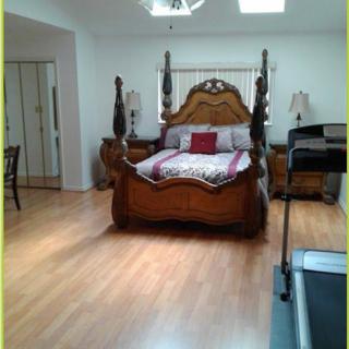 A spacious bedroom featuring a classic wooden bed and laminate flooring.
