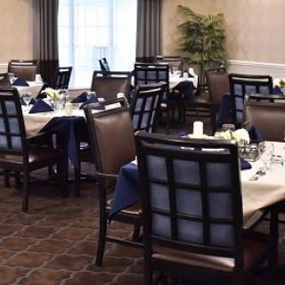 A neatly arranged dining area with set tables and chairs, ready for guests.
