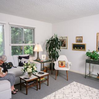 A cozy living room with modern decor, featuring a sofa, indoor plants, and artwork.