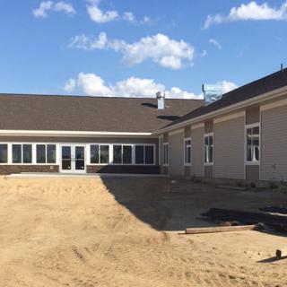 A newly constructed building with sandy surroundings under a clear blue sky.