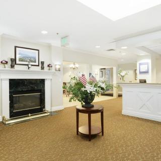 A well-lit lobby area featuring a reception desk, fireplace, and decorative plants.