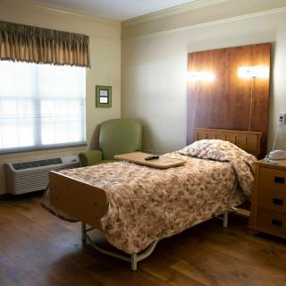 A hospital room with a single bed, chair, and window.