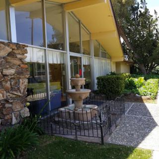 A modern architectural structure featuring a decorative fountain and landscaped gardens.