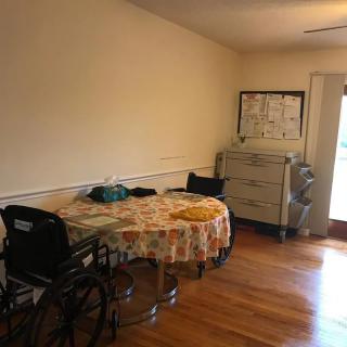 A nursing home room with a wheelchair, table, and medical equipment.