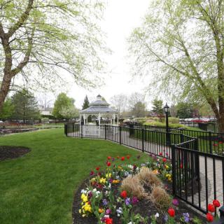 A serene park landscape featuring a gazebo surrounded by lush greenery and colorful flower beds.