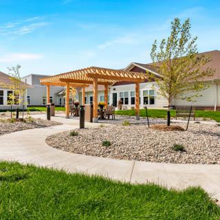 A beautifully landscaped outdoor area featuring a wooden pergola, garden paths, and surrounding greenery.