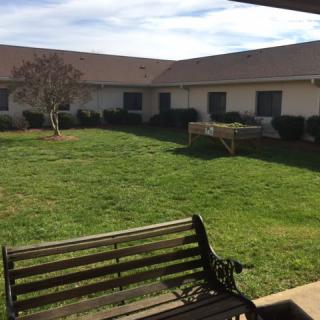 A peaceful courtyard with a bench and well-maintained grass surrounded by a building.