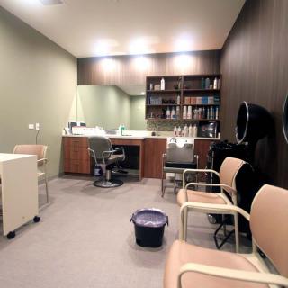 A modern salon interior with chairs, a mirror, and styling equipment.