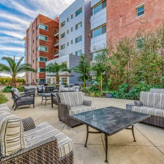 A modern outdoor seating area with stylish furniture surrounded by greenery and urban architecture.