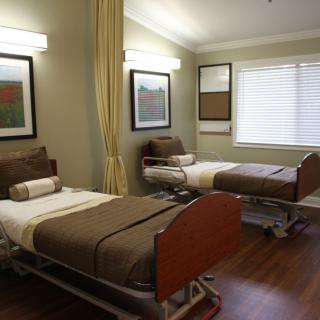 A hospital room with two neatly arranged patient beds and medical equipment.