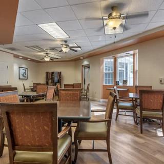 A spacious dining area with wooden tables and chairs, ceiling fans, and ample lighting.
