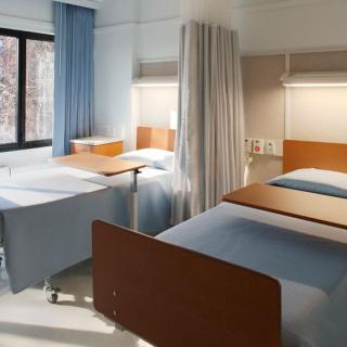A hospital room with multiple beds and a curtain divider.