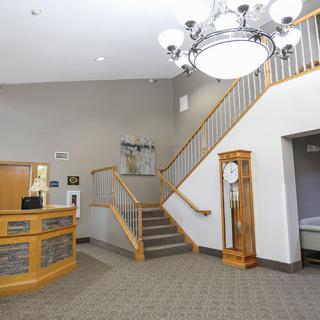 A spacious reception area featuring a staircase, clock, and chandelier.