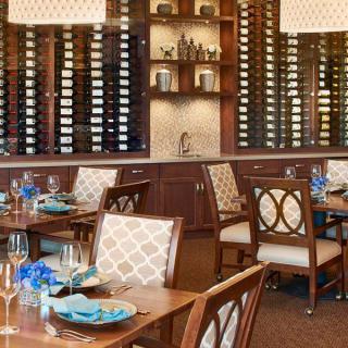 A cozy restaurant dining area with elegant table settings and a wall of wine racks.
