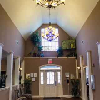 A warmly lit lobby featuring a chandelier and large window with indoor plants.