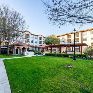 A residential building with manicured lawns and trees surrounding it, showcasing a serene and well-maintained landscape.