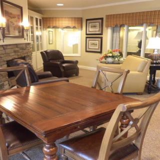 A cozy living room with a wooden table and chairs, a fireplace, and comfortable seating areas.