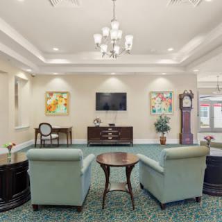 A cozy living room with comfortable armchairs, a central table, a flat-screen TV, and decorative artwork on the walls.