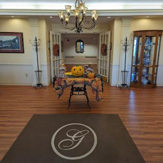A welcoming lobby area featuring a stylish chandelier, wooden flooring, and decorative furnishings.