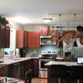 A modern kitchen with stainless steel appliances, featuring a central island and hanging pots and pans.