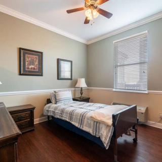 A cozy bedroom with a single bed, wooden furniture, and a ceiling fan.