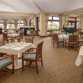An elegant restaurant dining area with neatly arranged tables and chairs, featuring large windows and tasteful decor.