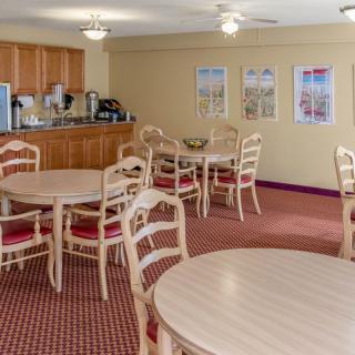 A cozy dining area with multiple tables and chairs, featuring a coffee station in the corner.