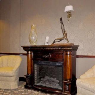 A cozy living room setup featuring a classic wooden fireplace flanked by two beige armchairs.