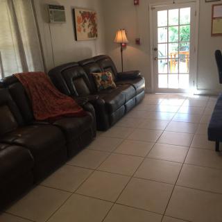 A cozy living room with a leather sofa, floor lamp, and tiled flooring.